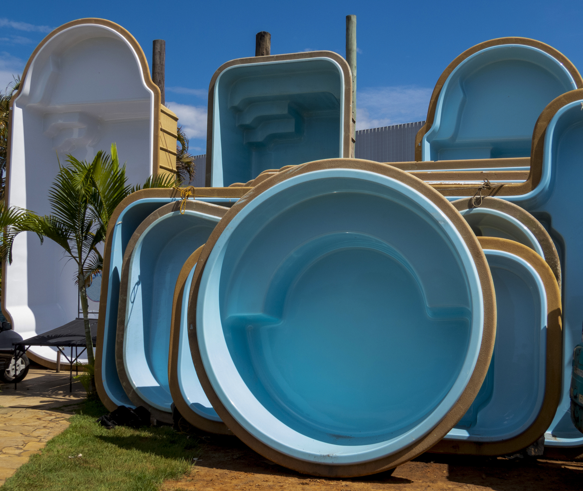 Blue and white fiberglass pools on display outside for sale.
