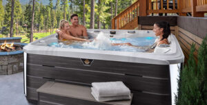 Two women and a man enjoying time in a Marquis Crown hot tub outside.