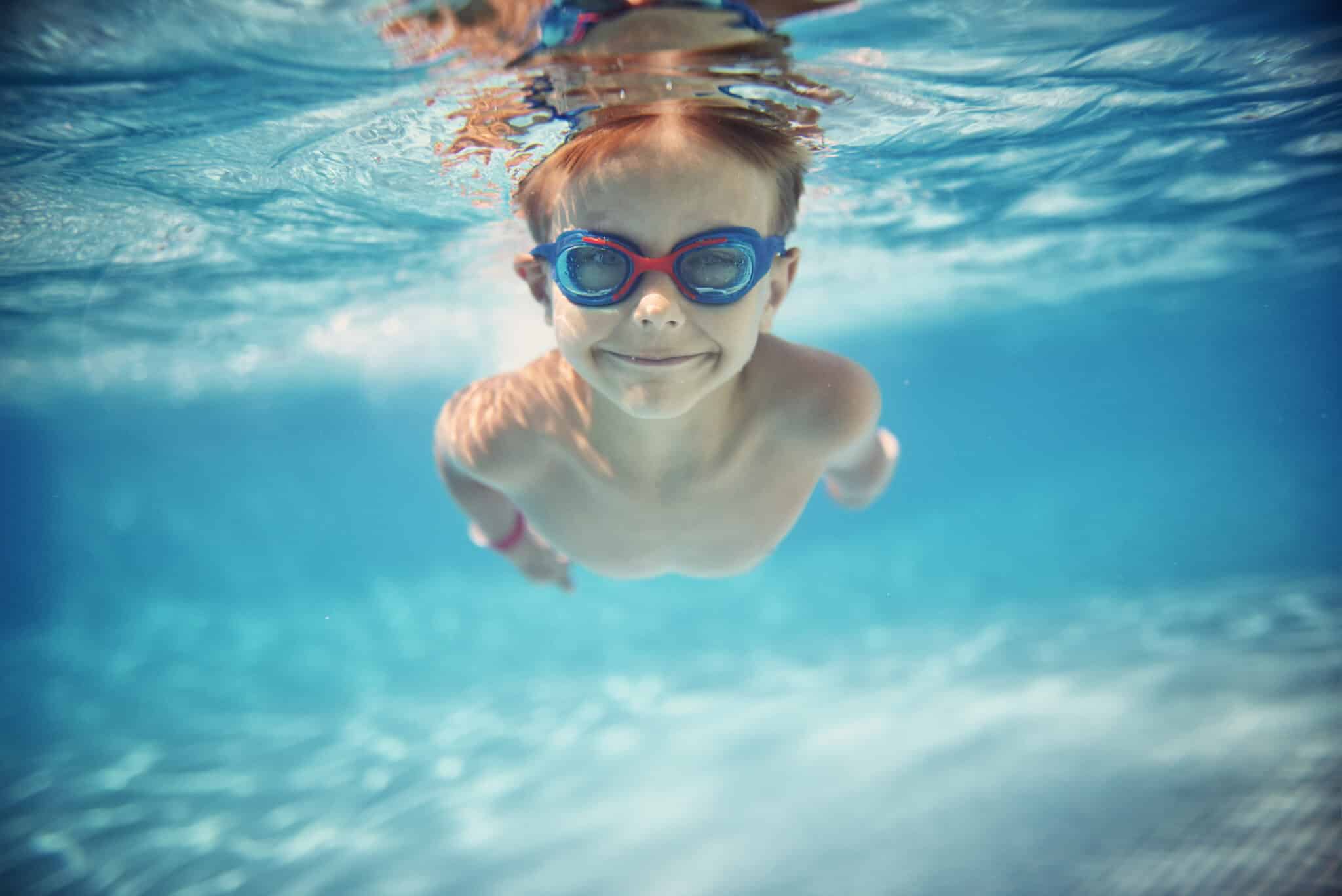 Portrait of smiling little boy enjoying an underwater swim in the pool towards the camera.