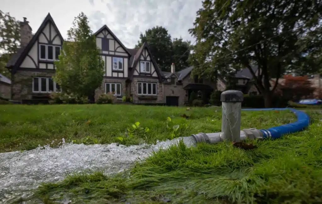 Water draining from a backyard swimming pool through a discharge hose during seasonal pool opening or maintenance service.
