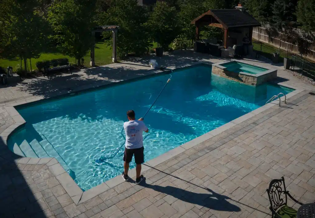 Pool service technician cleaning pool deck and surrounding area during spring pool opening