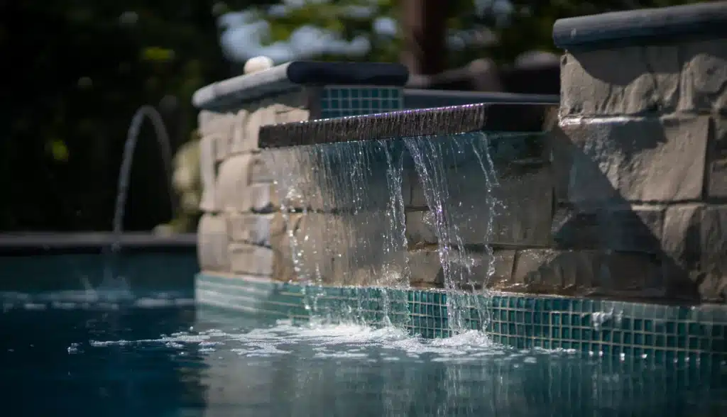 Spa with cascading waterfall feature connected to backyard swimming pool