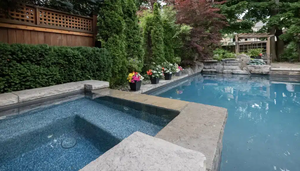 Backyard swimming pool and attached spa surrounded by landscaped garden and patio seating at residential home in Ontario.