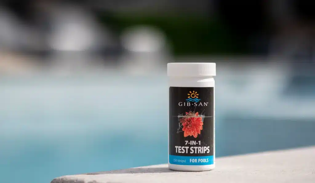 Gib-San Pools 7-in-1 pool water test strips container placed beside a backyard swimming pool for testing pool water chemistry.
